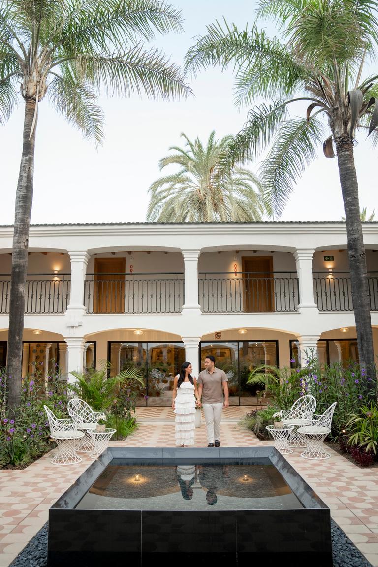 Couple walking through a courtyard lined with palm trees