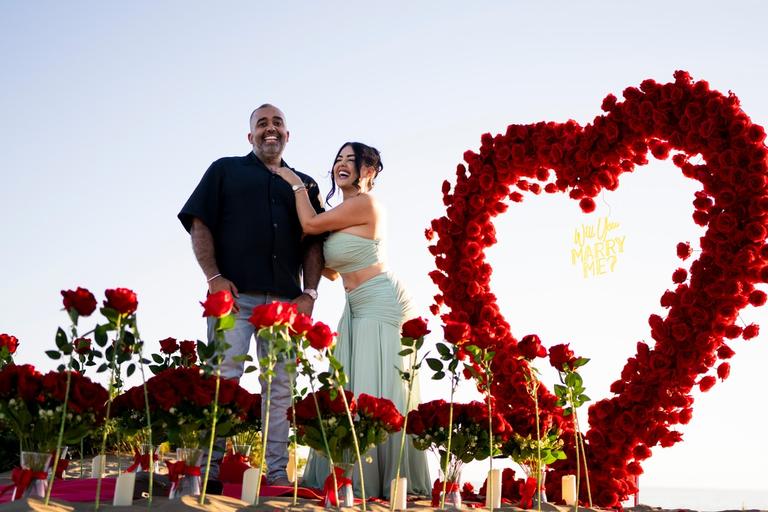Couple laughing together just after the proposal, the rose heart beside them